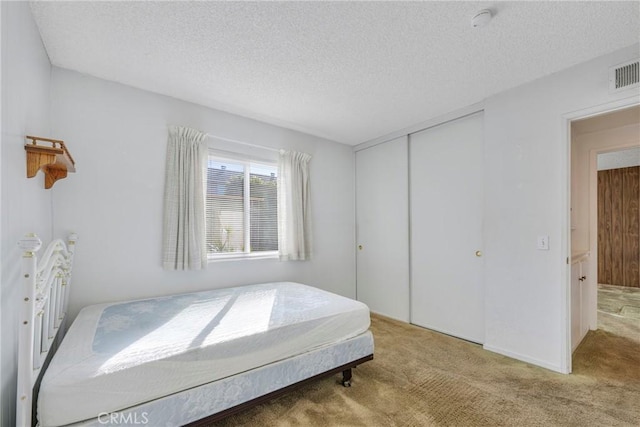 carpeted bedroom featuring a textured ceiling and a closet