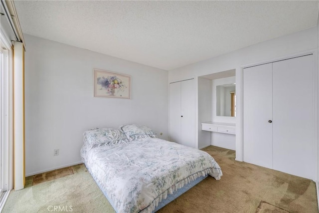 carpeted bedroom with a textured ceiling and two closets