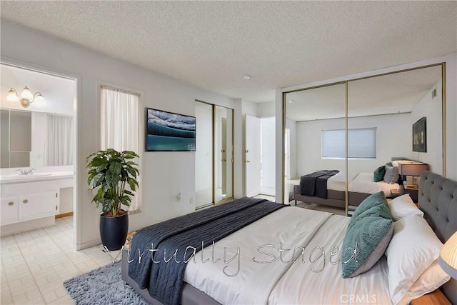 bedroom featuring sink, a textured ceiling, and ensuite bath