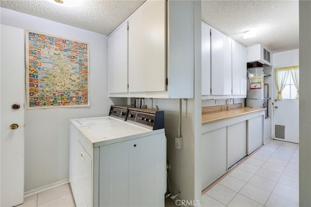 washroom with washing machine and dryer, cabinets, a textured ceiling, and water heater