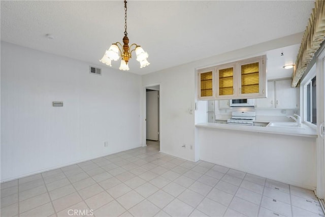 kitchen featuring pendant lighting, white appliances, an inviting chandelier, sink, and kitchen peninsula