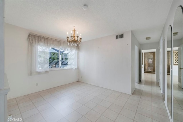 unfurnished dining area with light tile patterned floors, an inviting chandelier, and a textured ceiling