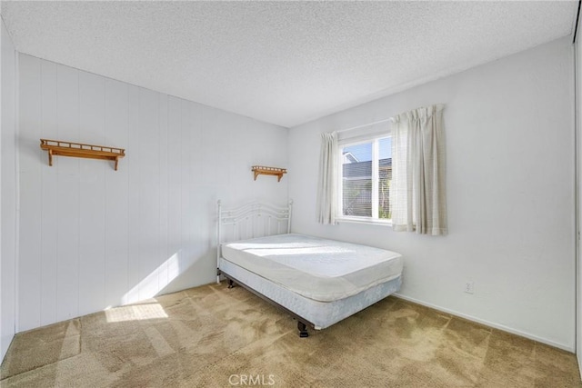 bedroom with a textured ceiling and light colored carpet