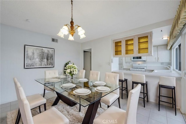 dining space featuring sink, light tile patterned floors, and an inviting chandelier