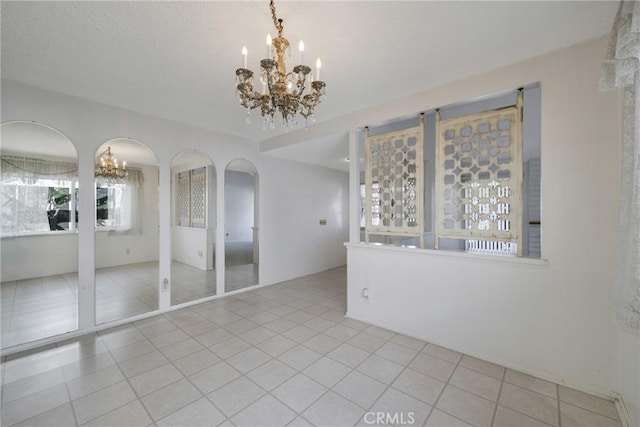 spare room featuring light tile patterned floors and a chandelier