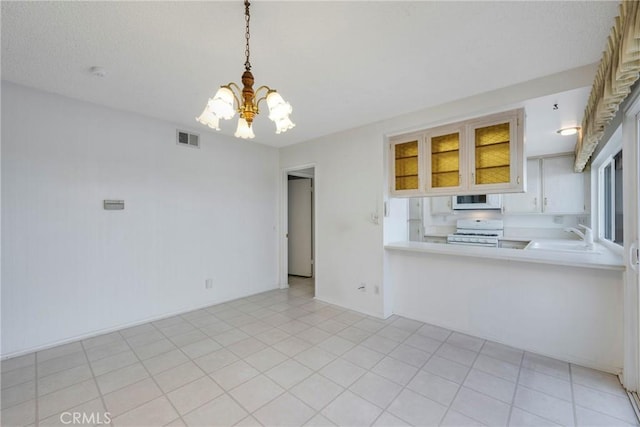 kitchen featuring kitchen peninsula, a notable chandelier, white appliances, hanging light fixtures, and sink