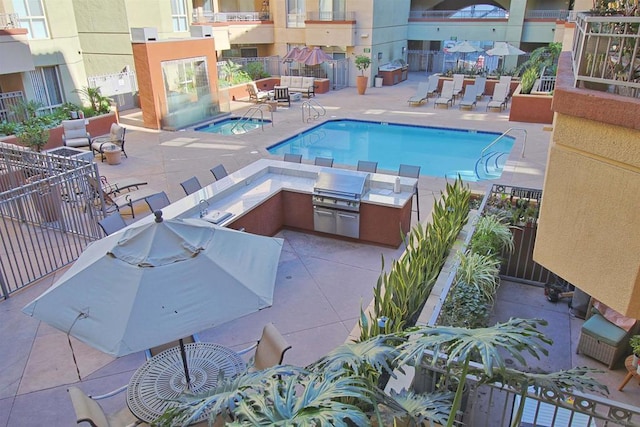 view of swimming pool featuring grilling area, a patio, and an outdoor kitchen