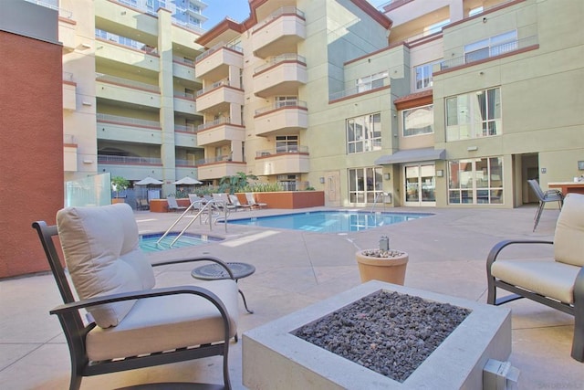 view of pool with an outdoor fire pit and a patio area