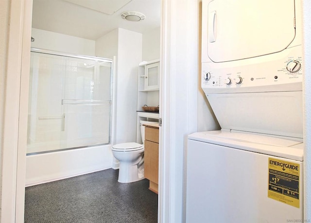 full bathroom featuring stacked washer / dryer, vanity, shower / bath combination with glass door, and toilet