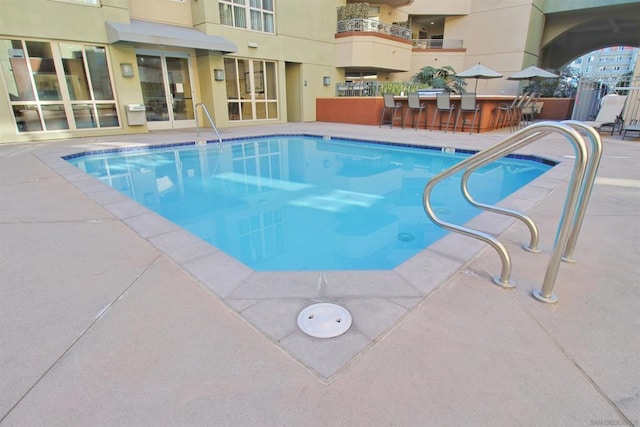 view of pool with exterior bar and a patio area