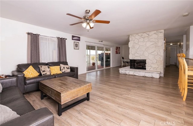 living room with ceiling fan, light hardwood / wood-style floors, and a fireplace