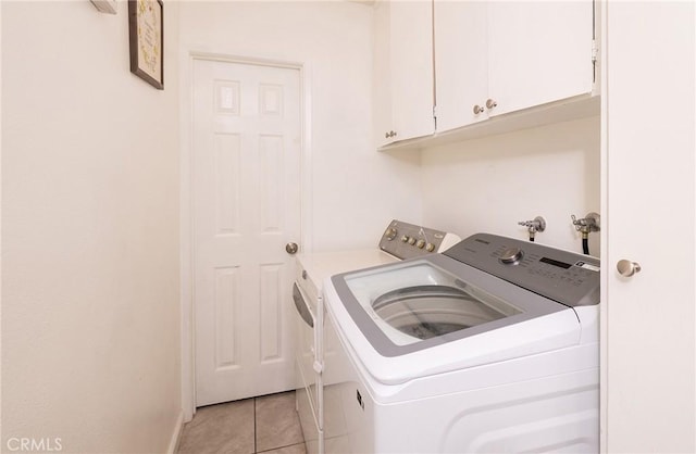 laundry room featuring cabinets, separate washer and dryer, and light tile patterned floors