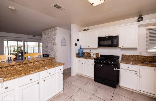 kitchen with light tile patterned flooring, dark stone countertops, white cabinets, and black appliances