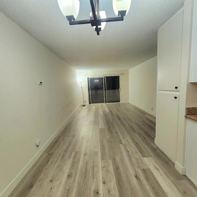 interior space with a chandelier, light hardwood / wood-style floors, and a textured ceiling