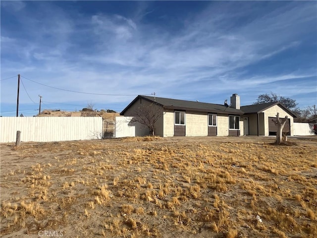 view of side of property with a gate, fence, a garage, and a chimney