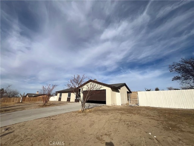 view of property exterior with concrete driveway, a garage, and fence