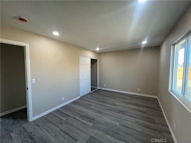 unfurnished bedroom with a closet and dark wood-type flooring