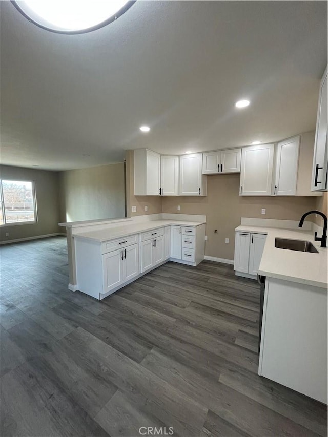 kitchen featuring dark wood-type flooring, sink, white cabinetry, and kitchen peninsula