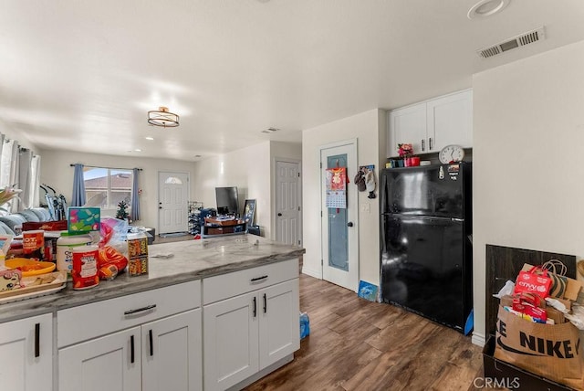 kitchen featuring black fridge, white cabinetry, light stone countertops, and dark wood-type flooring