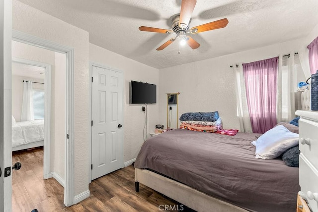 bedroom with a textured ceiling, ceiling fan, and dark hardwood / wood-style floors