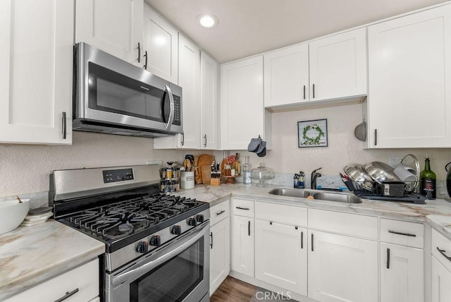 kitchen with sink, white cabinetry, light stone countertops, and appliances with stainless steel finishes