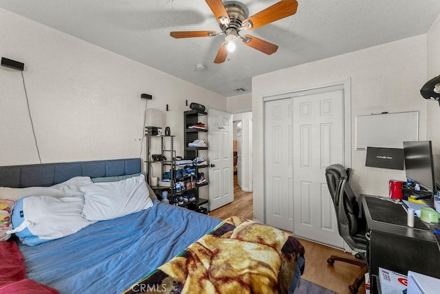 bedroom featuring ceiling fan, light hardwood / wood-style flooring, a closet, and a textured ceiling