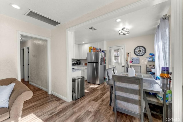 kitchen with white cabinetry, stainless steel refrigerator, and light hardwood / wood-style flooring