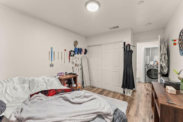 bedroom with washer / clothes dryer, a closet, and light wood-type flooring