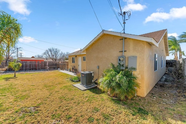 rear view of property with central air condition unit and a lawn