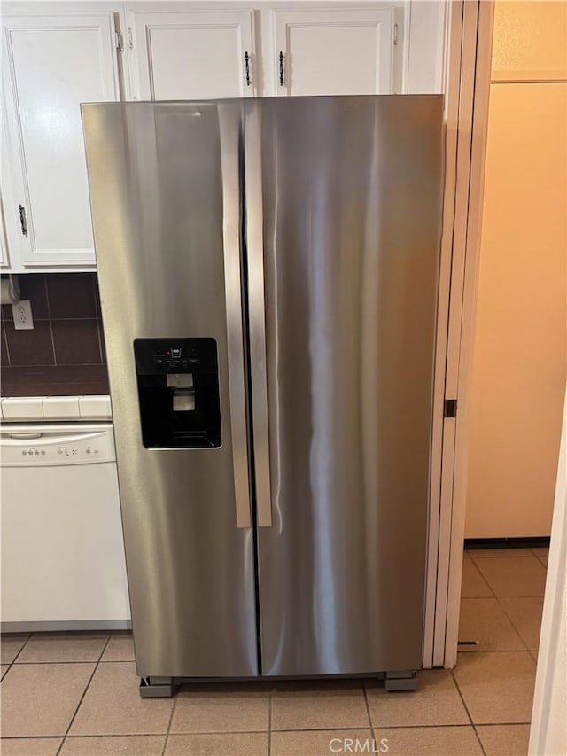 kitchen with stainless steel refrigerator with ice dispenser, light tile patterned floors, white cabinetry, and white dishwasher