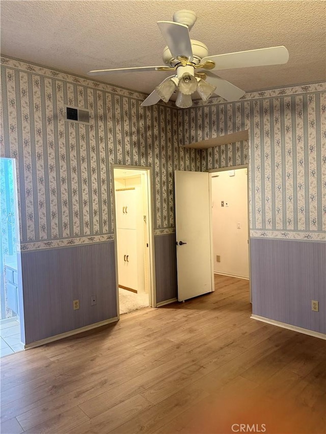 spare room with ceiling fan, a textured ceiling, and hardwood / wood-style floors