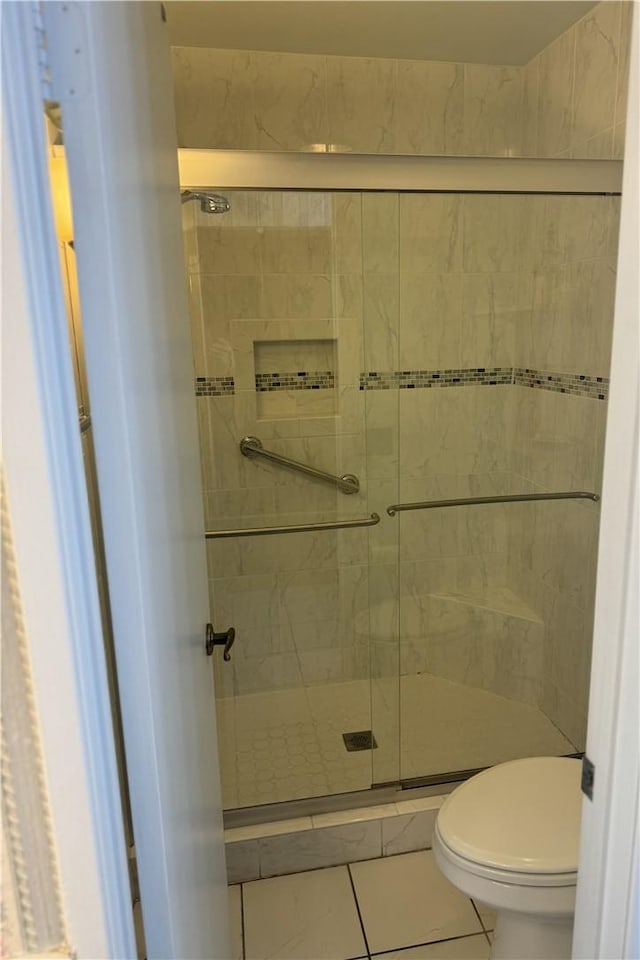 bathroom with an enclosed shower, tile patterned floors, and toilet