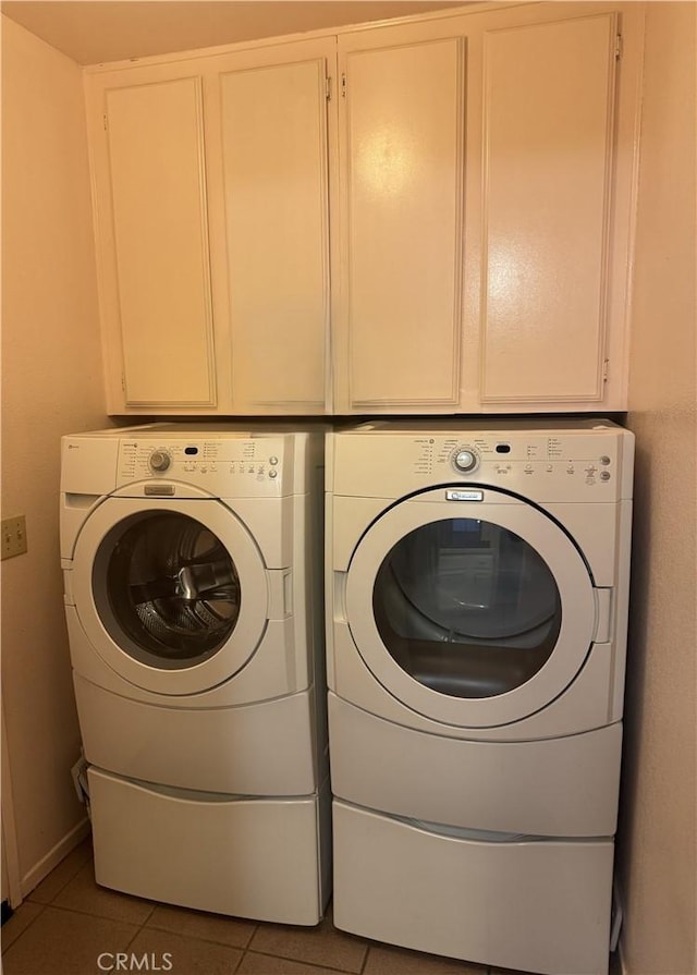 washroom with dark tile patterned floors, separate washer and dryer, and cabinets