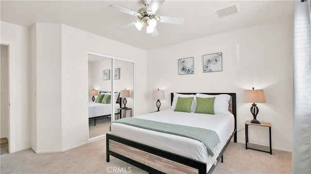 bedroom featuring ceiling fan, a closet, and light colored carpet