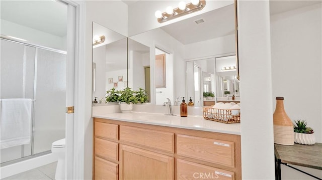 bathroom featuring vanity, toilet, tile patterned flooring, and a shower with door