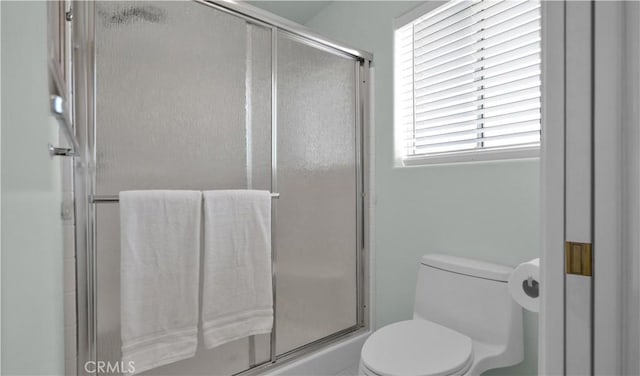 bathroom with a shower with shower door and toilet