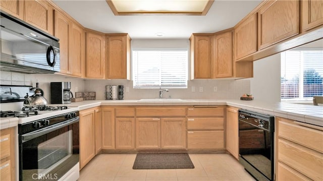 kitchen with tasteful backsplash, sink, black dishwasher, light tile patterned floors, and range with gas stovetop