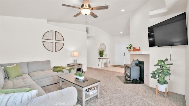 carpeted living room with vaulted ceiling, ceiling fan, and a wood stove