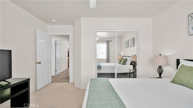 carpeted bedroom featuring ceiling fan and a closet