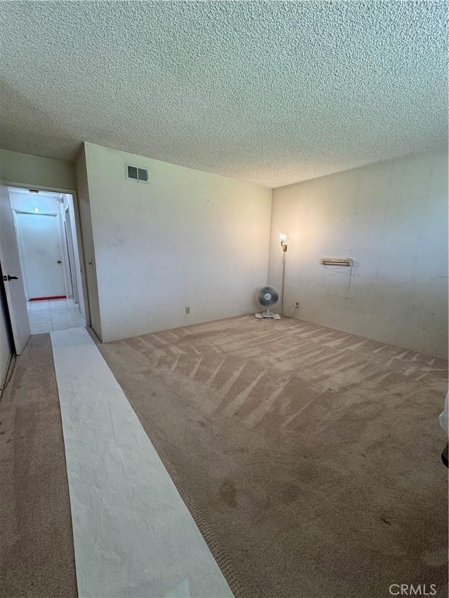 spare room featuring a textured ceiling and light colored carpet