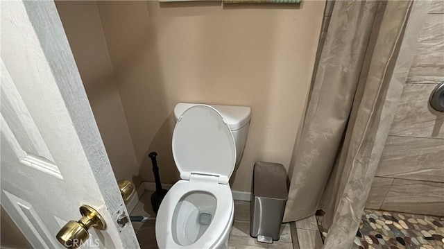 bathroom featuring toilet and curtained shower