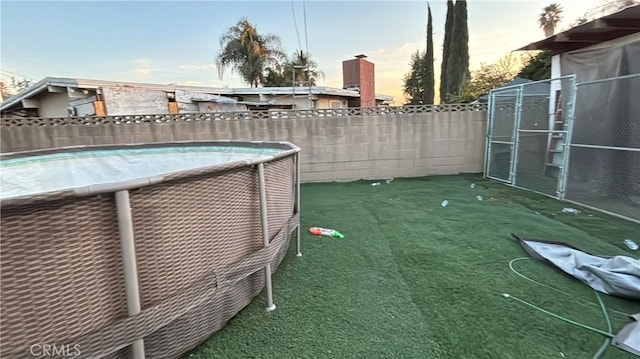 yard at dusk featuring a fenced in pool