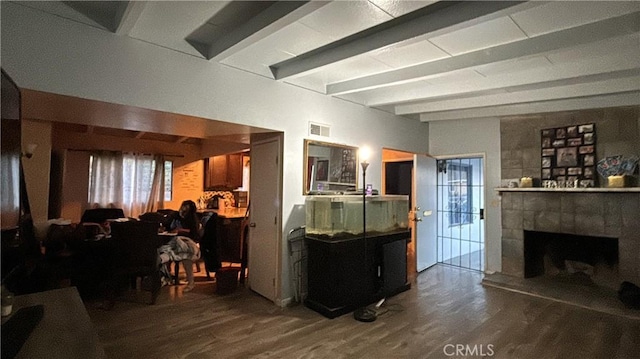 living room featuring beam ceiling, a tiled fireplace, and hardwood / wood-style flooring