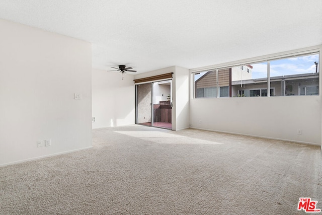 unfurnished room with ceiling fan, a textured ceiling, and light carpet