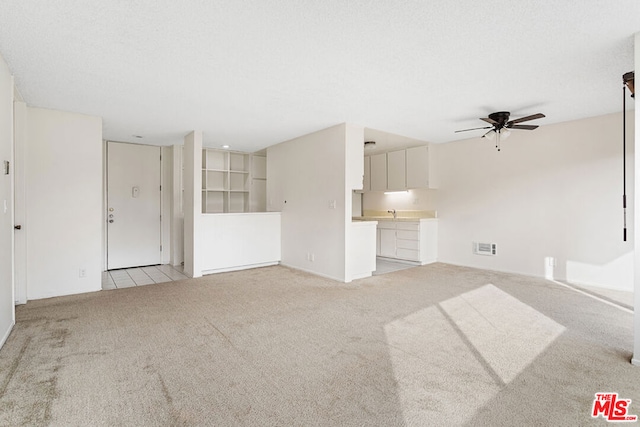 unfurnished living room featuring ceiling fan and light colored carpet