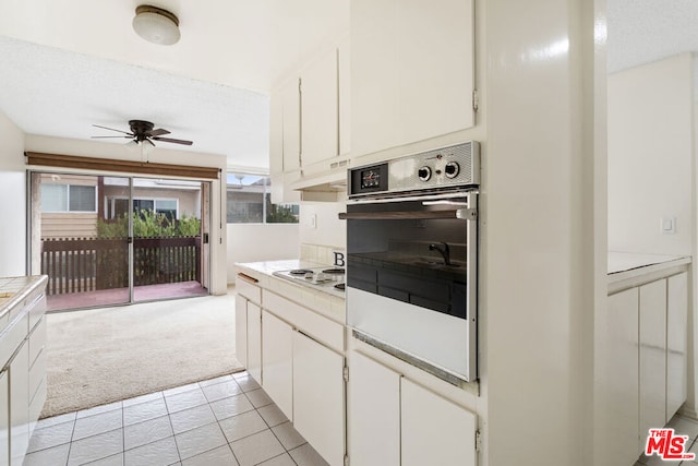 kitchen featuring ceiling fan, white cabinets, white gas stovetop, and light colored carpet