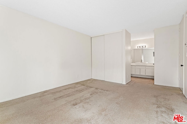 unfurnished bedroom featuring light carpet, a closet, and connected bathroom