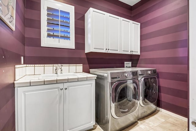 clothes washing area featuring cabinets, sink, light tile patterned floors, and washing machine and dryer