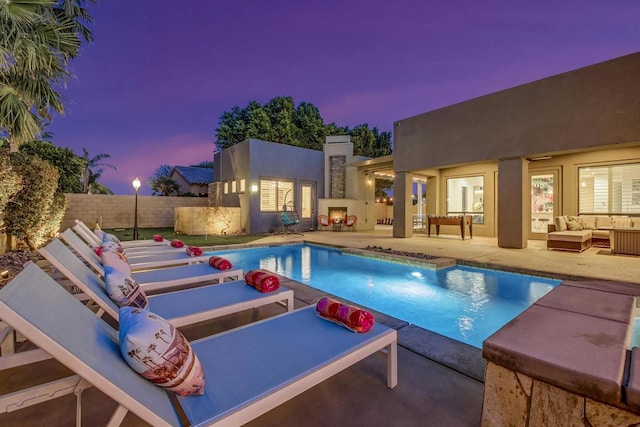 pool at dusk featuring outdoor lounge area and a patio