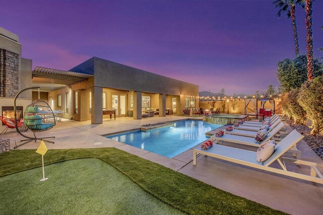 pool at dusk with an outdoor hangout area, a hot tub, and a patio